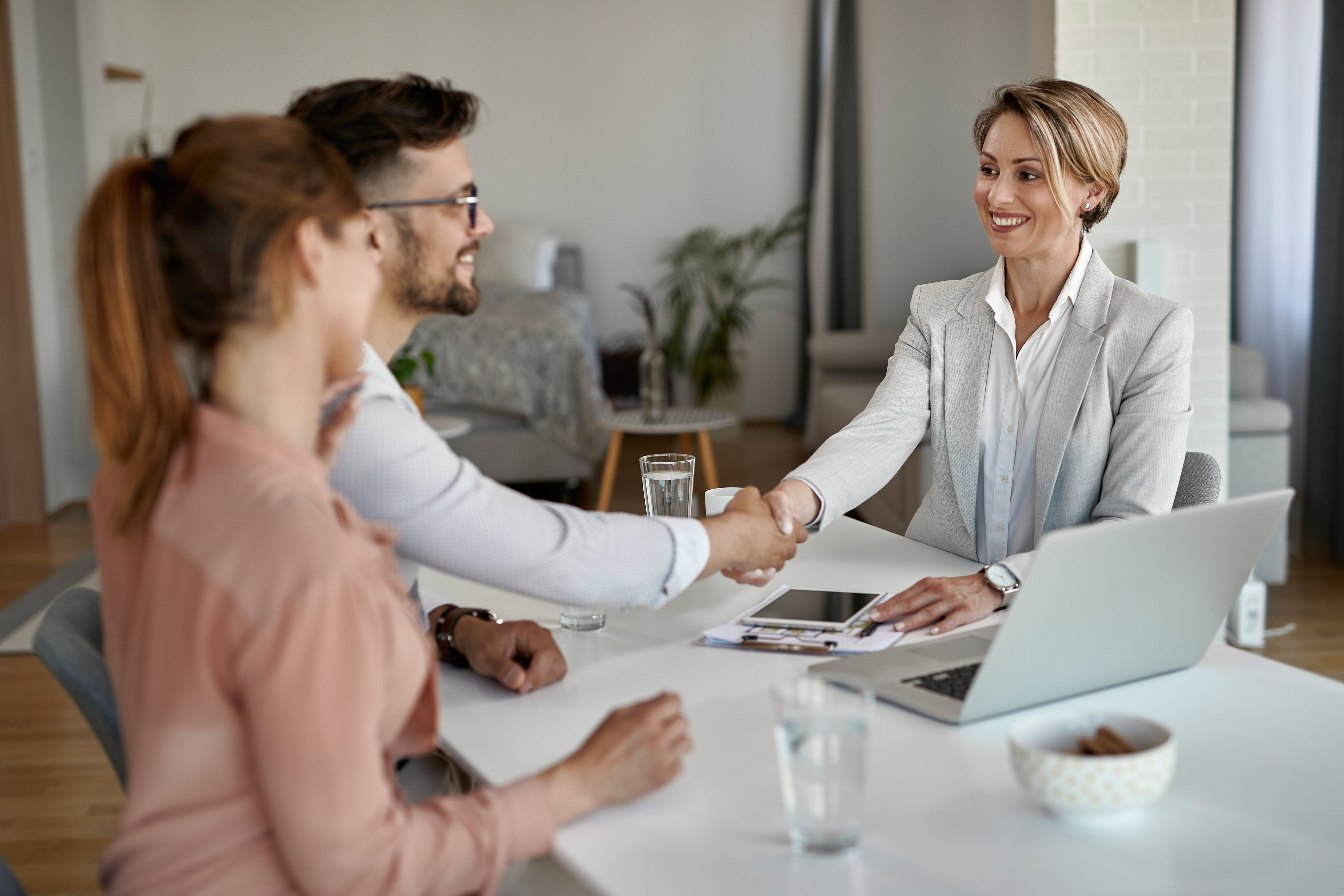 feliz-agente-inmobiliario-estrechando-la-mano-de-una-pareja-en-una-reunion-en-la-oficina